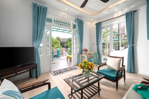 a living room with blue curtains and a tv at House Happy Clam Hoi An in An Bang