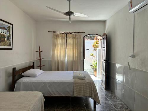 a bedroom with two beds and a window with a cross at La Mar Paraty Hospedaria 06 in Paraty