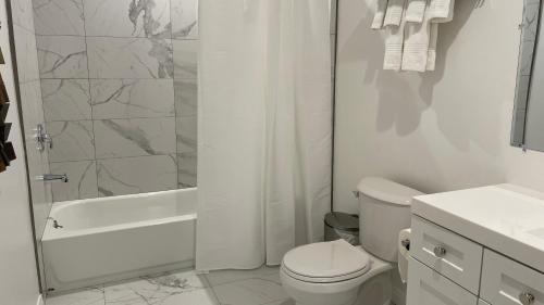 a white bathroom with a toilet and a shower at Luxury mini house in Hughes-Canoga Park Heliport