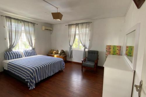 a bedroom with a bed and a chair and two windows at Le Botanic Oasis 3 beds summer vacation private villa with private pool and garden albion in Albion