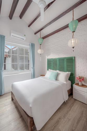 a bedroom with a large white bed and a window at House Happy Clam Hoi An in An Bang