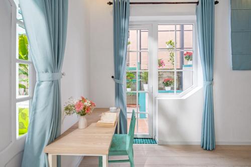 a dining room with blue curtains and a table and a window at House Happy Clam Hoi An in An Bang