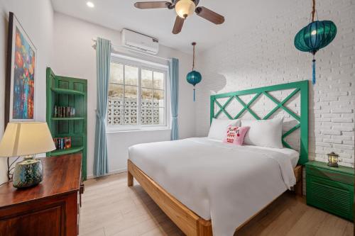 a bedroom with a bed with a green headboard and a window at House Happy Clam Hoi An in An Bang