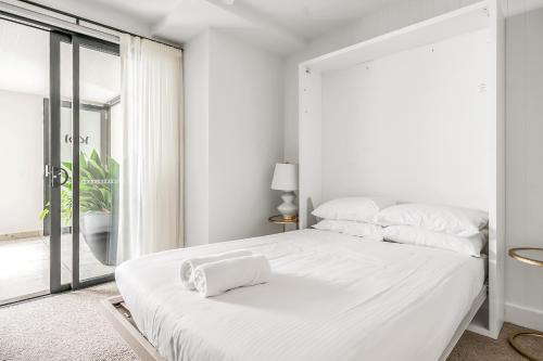 a white bedroom with a large white bed with white pillows at Stunning designer 3 Bed 2 bath opp Long Reef Golf Course in Collaroy