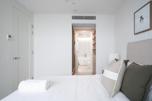 a bedroom with a white bed and a bathroom at Stunning designer 3 Bed 2 bath opp Long Reef Golf Course in Collaroy