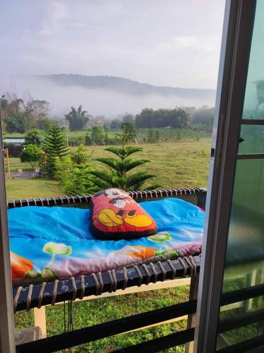 a pillow sitting on a bed in a window at หนาวกลางหมอกโฮสเตย์ เขาค้อ in Phetchabun