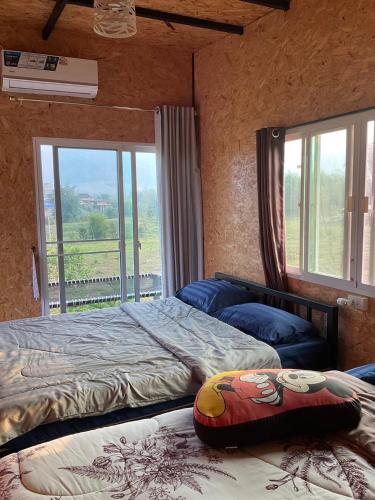 a bedroom with two beds and a large window at หนาวกลางหมอกโฮสเตย์ เขาค้อ in Phetchabun
