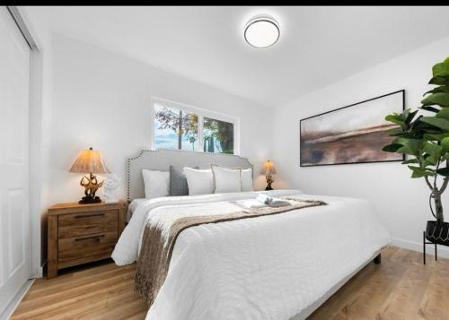 a white bedroom with a large bed and a table at Cozy beautiful house in Glendora