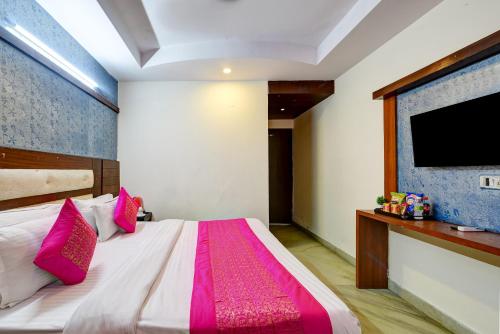 a bedroom with a bed with pink pillows and a flat screen tv at Hotel Re Pose Villa Walking Distance From New Delhi Railway Station and R K Ashram Metro Station in New Delhi
