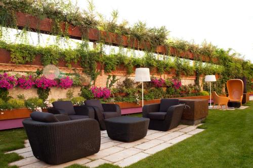 a garden with chairs and plants on a wall at Hotel AF Pesquera in Peñafiel