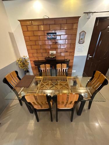 Una mesa de comedor de vidrio con sillas y una pared de ladrillos. en Woodfins Stay, en Mussoorie