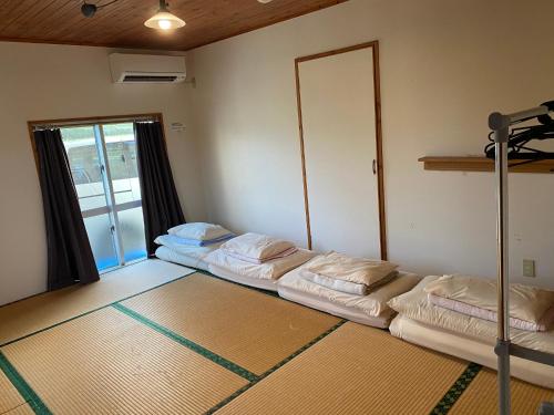 a room with three beds in it with a window at 8人乗りレンタカー無料ファミリー団体向け貸別荘珊瑚のサウナ in Miyako Island
