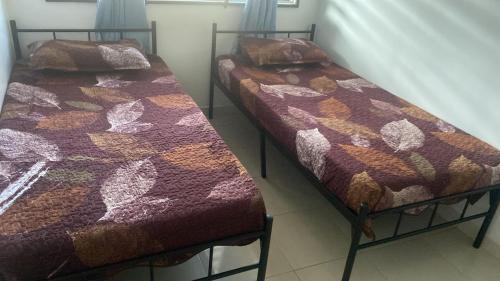 two beds sitting next to each other in a room at Ainun Homestay with private pool in Kuantan