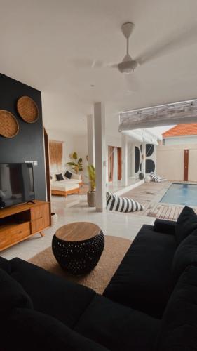 a living room with a couch and a table and a pool at Villa Hope Bali in Kerobokan