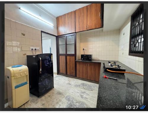 a kitchen with a stove and a black refrigerator at Villa Manor in Puducherry
