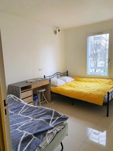 une chambre avec deux lits et un bureau et une fenêtre dans l'établissement YLt333, à Créteil