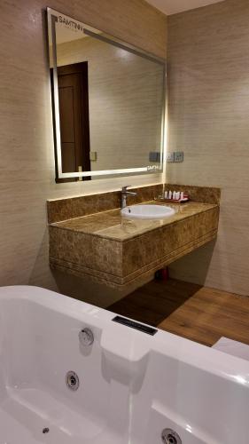a bathroom with a sink and a large mirror at Samtinn Hotel King Fahad in Riyadh