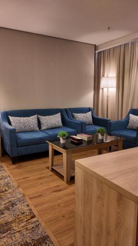a living room with a blue couch and tables at Samtinn Hotel King Fahad in Riyadh