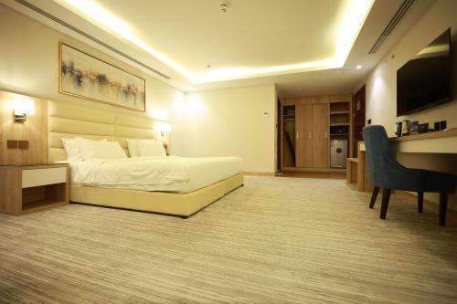 a hotel room with a bed and a desk and a chair at Samtinn Hotel King Fahad in Riyadh