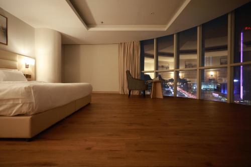 a hotel room with a bed and a desk and a window at Samtinn Hotel King Fahad in Riyadh