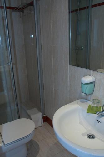 a bathroom with a toilet and a sink and a shower at Hotel Cuéntame in Burgos