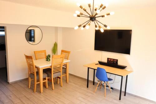 a dining room with a table and chairs and a television at Tranquila casa in Mexico City