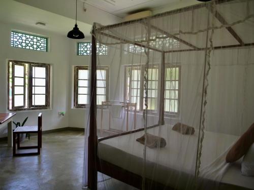 a bedroom with a canopy bed and a table at Kaela Green Villa in Ahangama