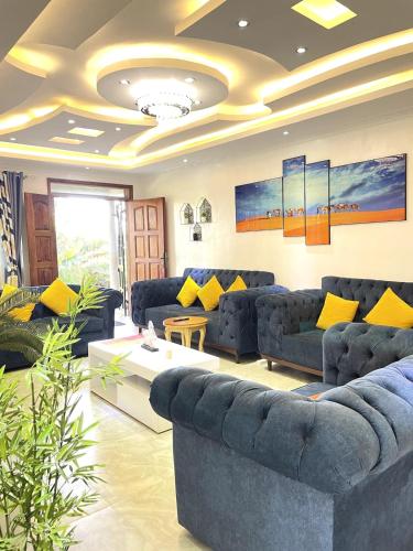 a living room with blue couches and yellow pillows at Aberdare Home Two Bedroom in Othaya