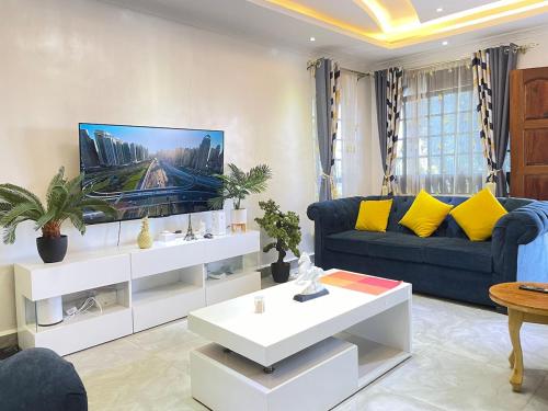 a living room with a blue couch and yellow pillows at Aberdare Home Two Bedroom in Othaya