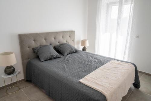 - une chambre avec un grand lit et une couette grise dans l'établissement Noscia Nivaledda - Stone house, with pool, à Porto-Vecchio