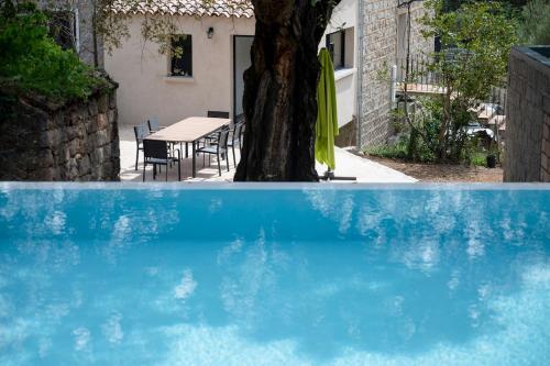 une piscine bleue avec un arbre et une table dans l'établissement Noscia Nivaledda - Stone house, with pool, à Porto-Vecchio