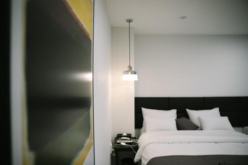 a bedroom with a bed with white sheets and a mirror at Gray hotel in Tongyeong