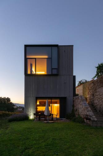a black house with a table and an umbrella at Melgaço Alvarinho Houses in Melgaço