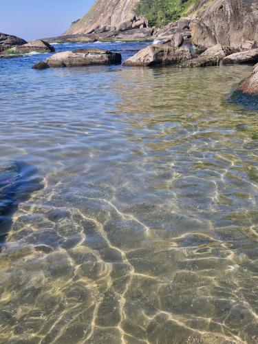 a body of water with rocks in the water at Suíte tripla com vista piscina em casa familiar de luxo em Itaipu in Niterói