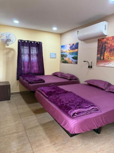 two beds in a room with purple sheets at Chidambaram Spiritual Stay in Chidambaram