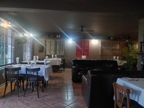 a dining room with white tables and chairs and lights at The Gateway Inn in Louis Trichardt