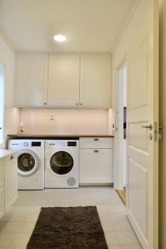 a kitchen with white cabinets and a washer and dryer at House near Umeå for rent in Umeå