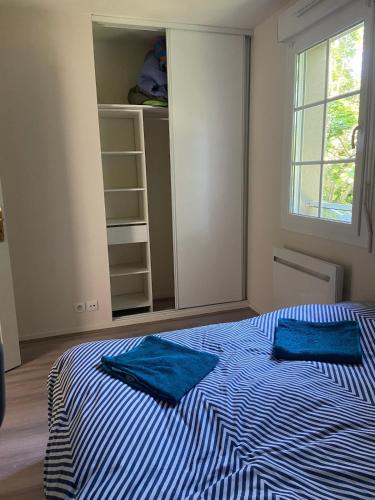 une chambre avec un lit avec deux oreillers bleus dessus dans l'établissement Maison de 100m2 avec jardin aux portes de Caen, à Hubert-Folie
