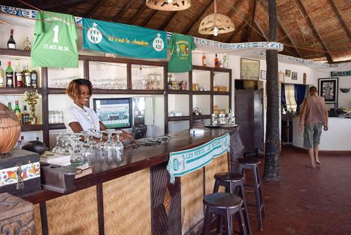 a woman sitting at a bar in a restaurant at Hôtel Les Cordons Bleus in Ndangane
