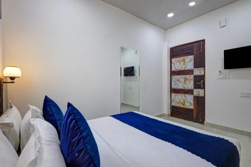 a bedroom with a bed with blue pillows at Hotel Warm Welcome Inn - Noida Sector 26 in Noida