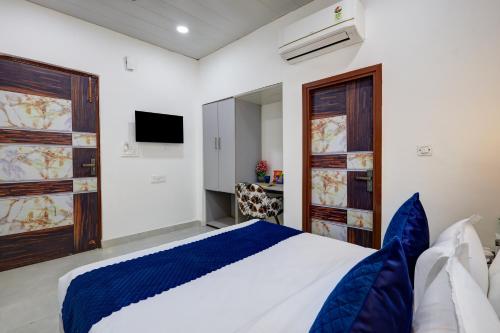 a bedroom with a blue and white bed and a tv at Hotel Warm Welcome Inn - Noida Sector 26 in Noida