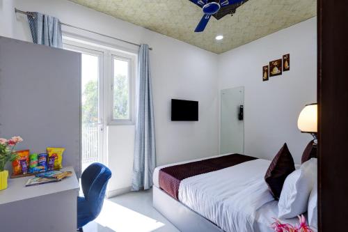 a bedroom with a bed and a desk and a window at Hotel Warm Welcome Inn - Noida Sector 26 in Noida