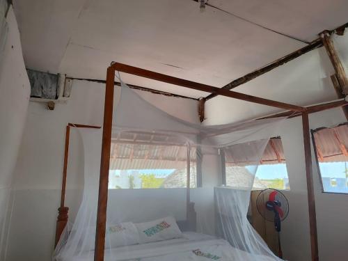 a bedroom with a canopy bed and a window at Rafiki Backpackers-hostel in Nungwi