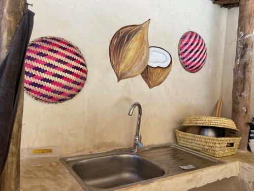 a kitchen with a sink and some vegetables on the wall at BOUGAIN VILLA -nice for couple in Nungwi