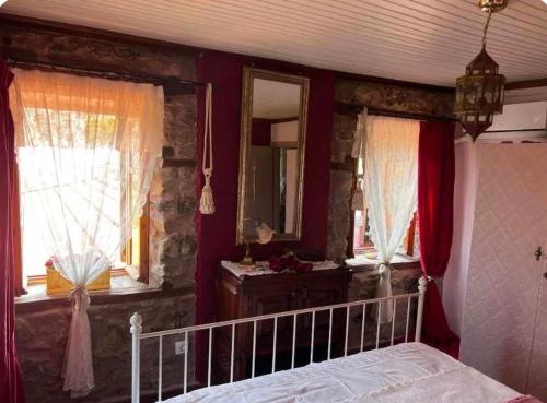 a bedroom with a bed and two windows with red curtains at Luxury suites in Villa Anasia, Olympia in Skotina