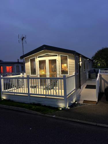 a small house with a porch and a white fence at Mimosa lodge in Little Clacton