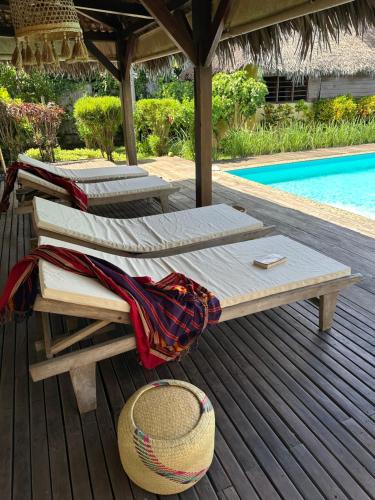 two beds on a deck next to a pool at La Parenthèse in Nosy Be