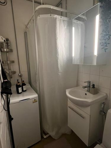 a white bathroom with a shower and a sink at Apartment in the center of the city in Pietarsaari in Pietarsaari