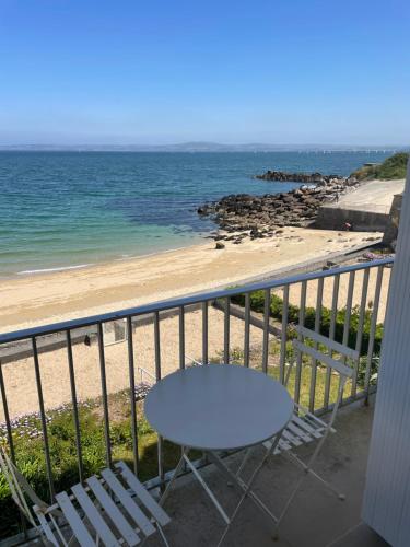 - stół i krzesła na balkonie z widokiem na plażę w obiekcie Paradis no Grenze Magnique vue mer w mieście Douarnenez