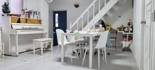 una sala da pranzo bianca con tavolo e sedie bianche di Lauren House a Daegu